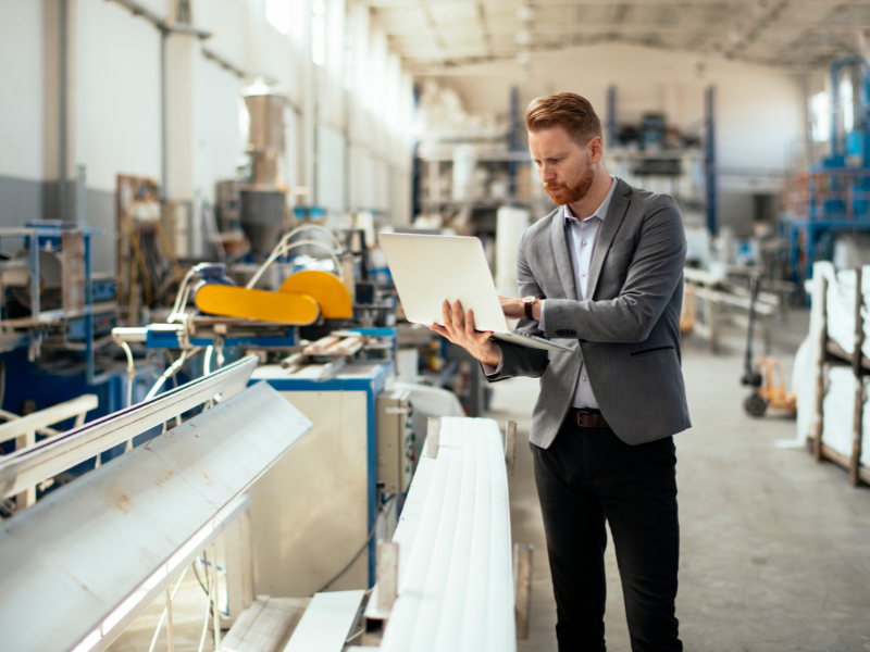 man working on laptop in manufacturing warehouse